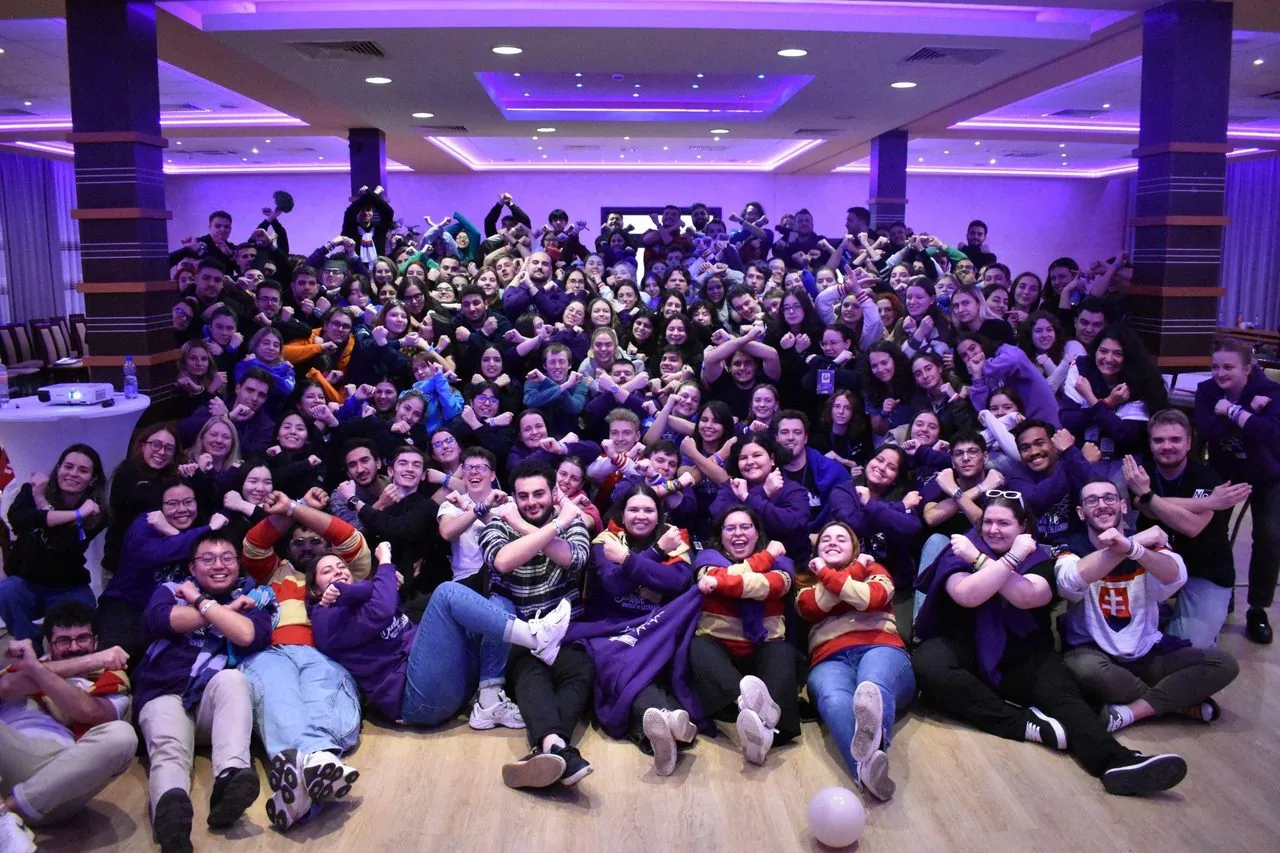 AIESEC delegates gathered in a large conference room, energetic group photo