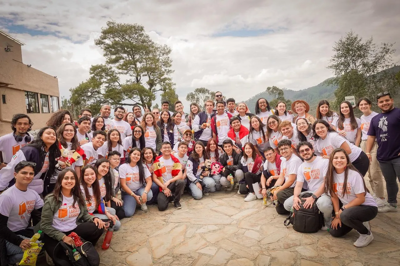 A large international AIESEC group gathered outdoors in AIESEC-branded shirts